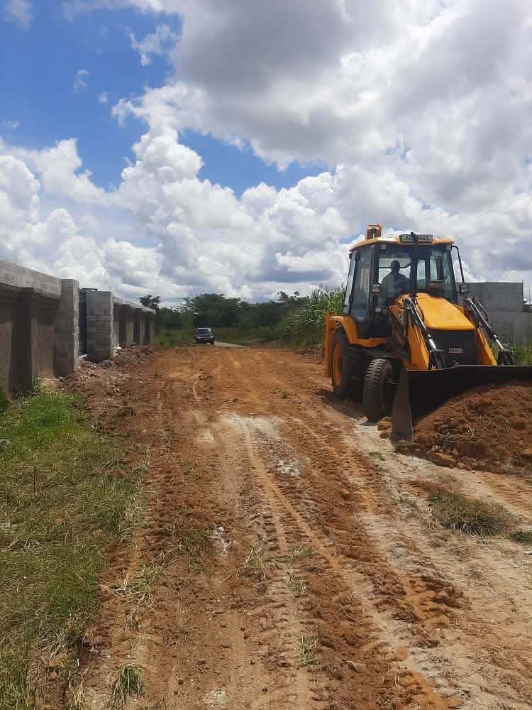 BMR backhoe grading an access road beside a boundary wall