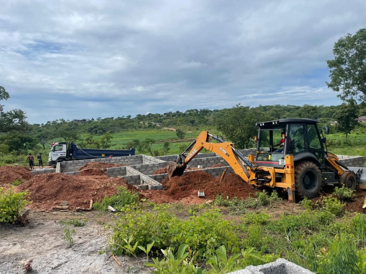 BMR backhoe loader excavating beside block foundations
