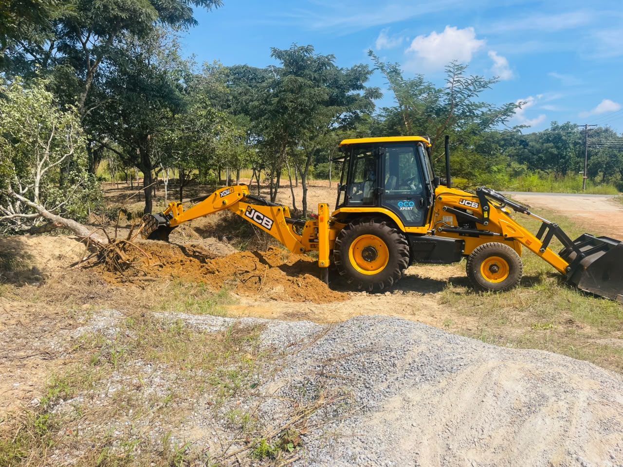 BMR backhoe loader at work near gravel stockpiles