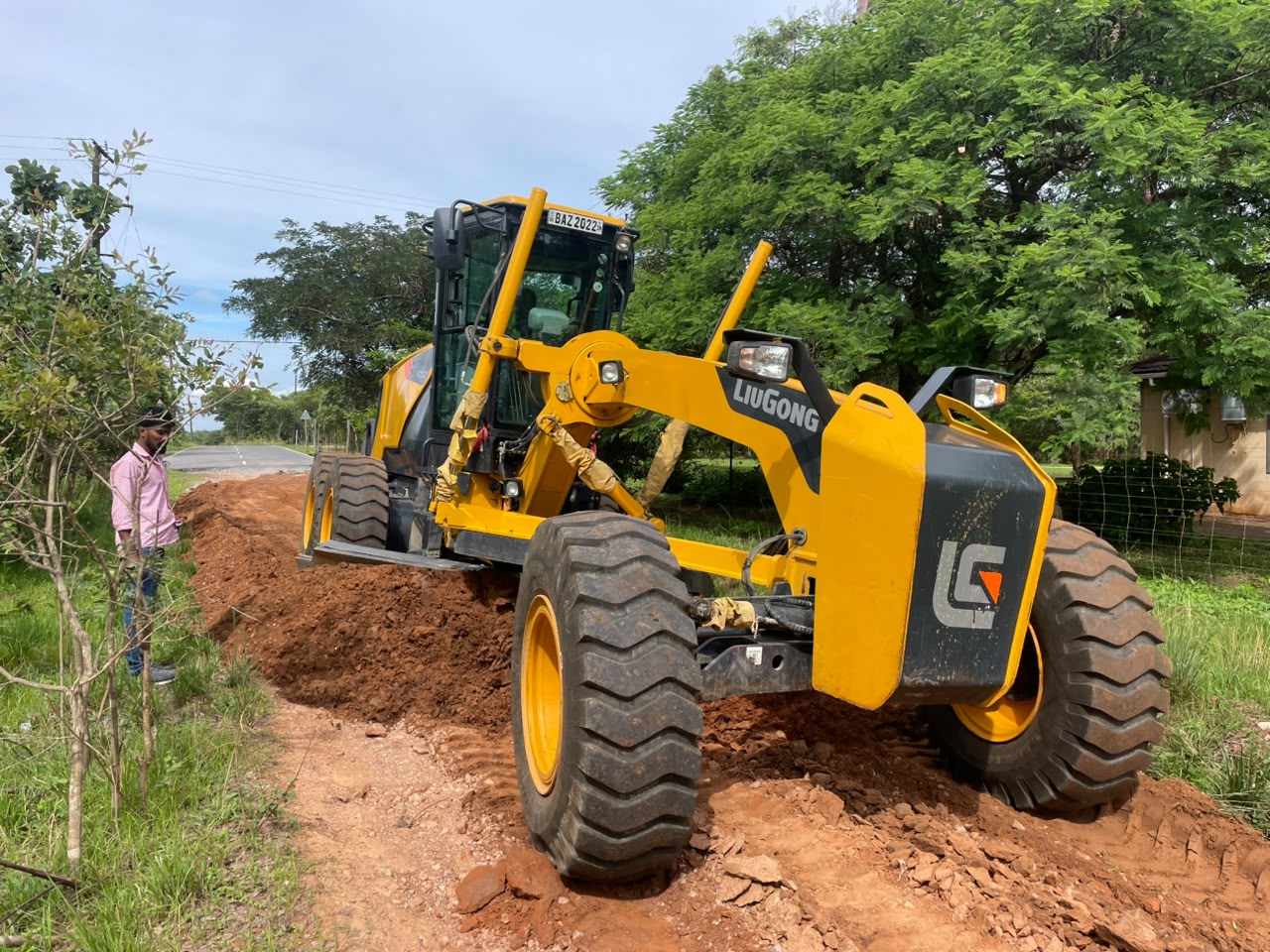 BMR motor grader cutting a road beside a worker